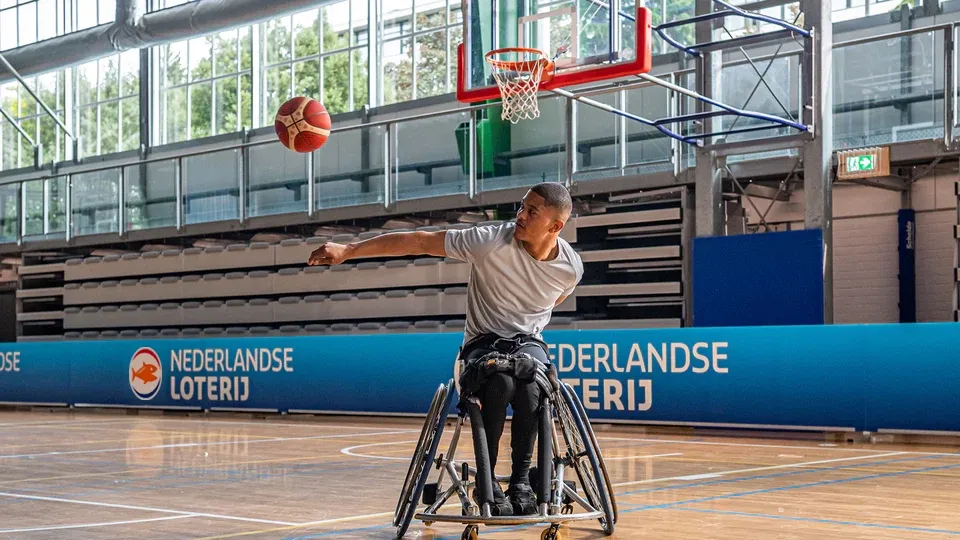 Wheelchair basketball player werpt een bal naar de basket.